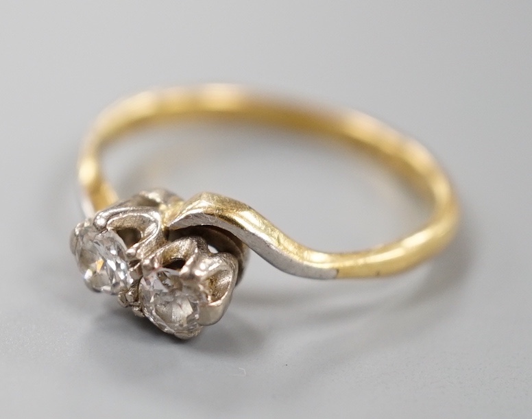 A yellow metal and plat, two stone diamond set crossover ring, size M, gross weight 2.8 grams.